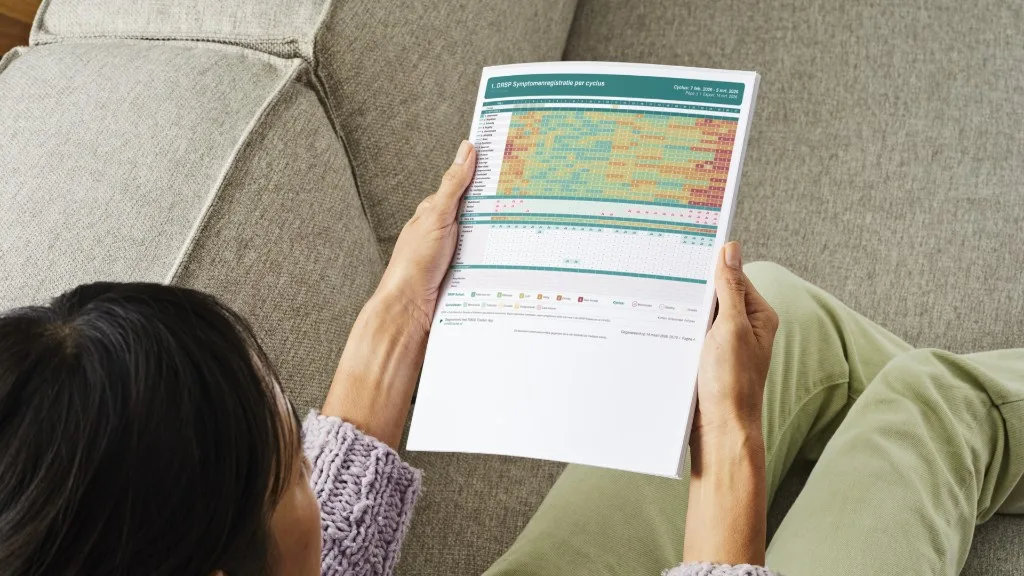Vrouw leest een geprint DRSP-symptoomrapport gegenereerd met de PMDD Tracker app